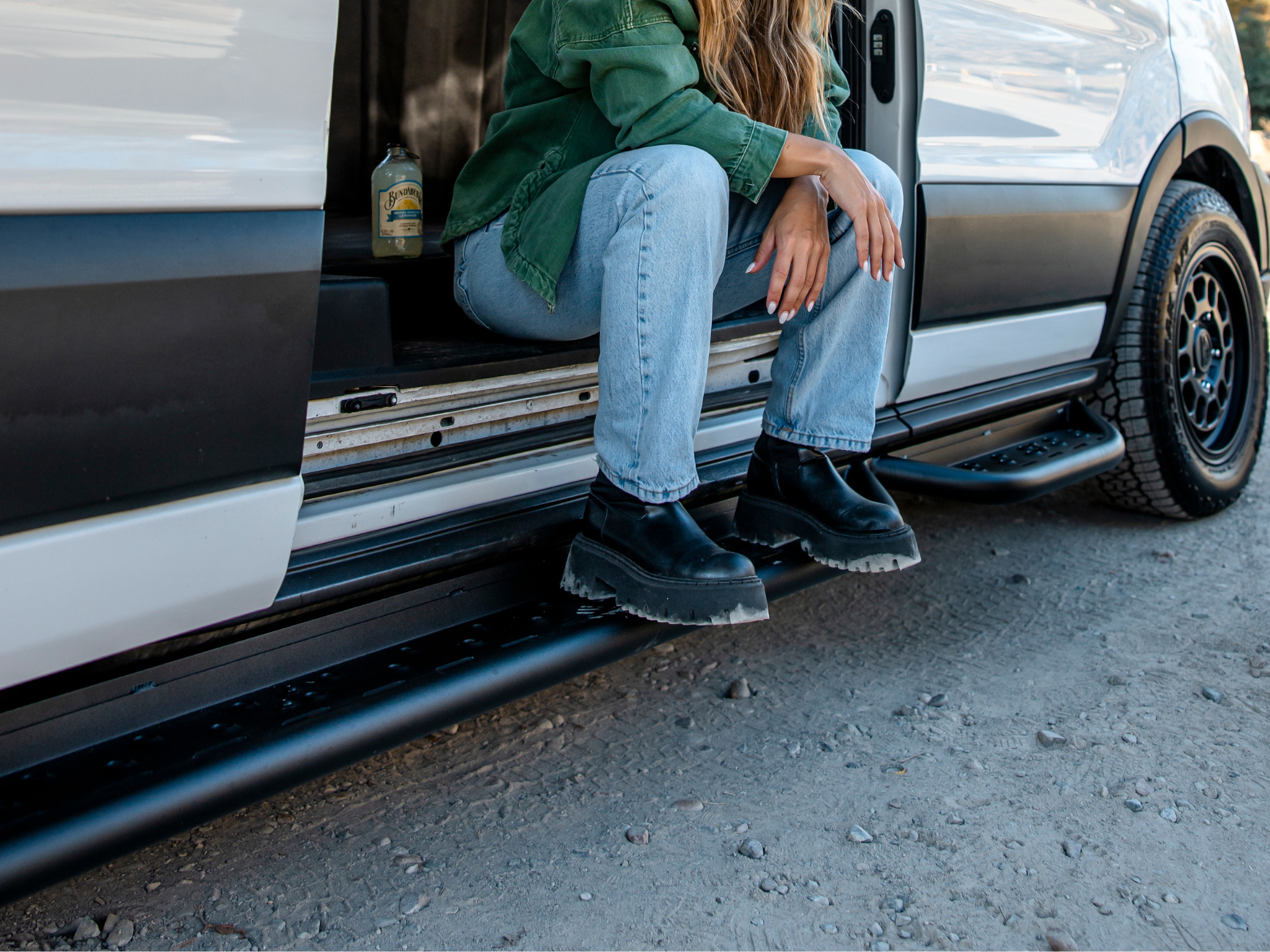 Black side steps under a Ford Transit with perforated tread for foot access