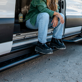 Black side steps under a Ford Transit with perforated tread for foot access