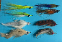 Fishing lure assortment with feathered flies in green, purple, orange-brown, white, and blue
