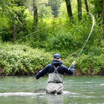 Fly fisherman casting a line on a river from a small boat