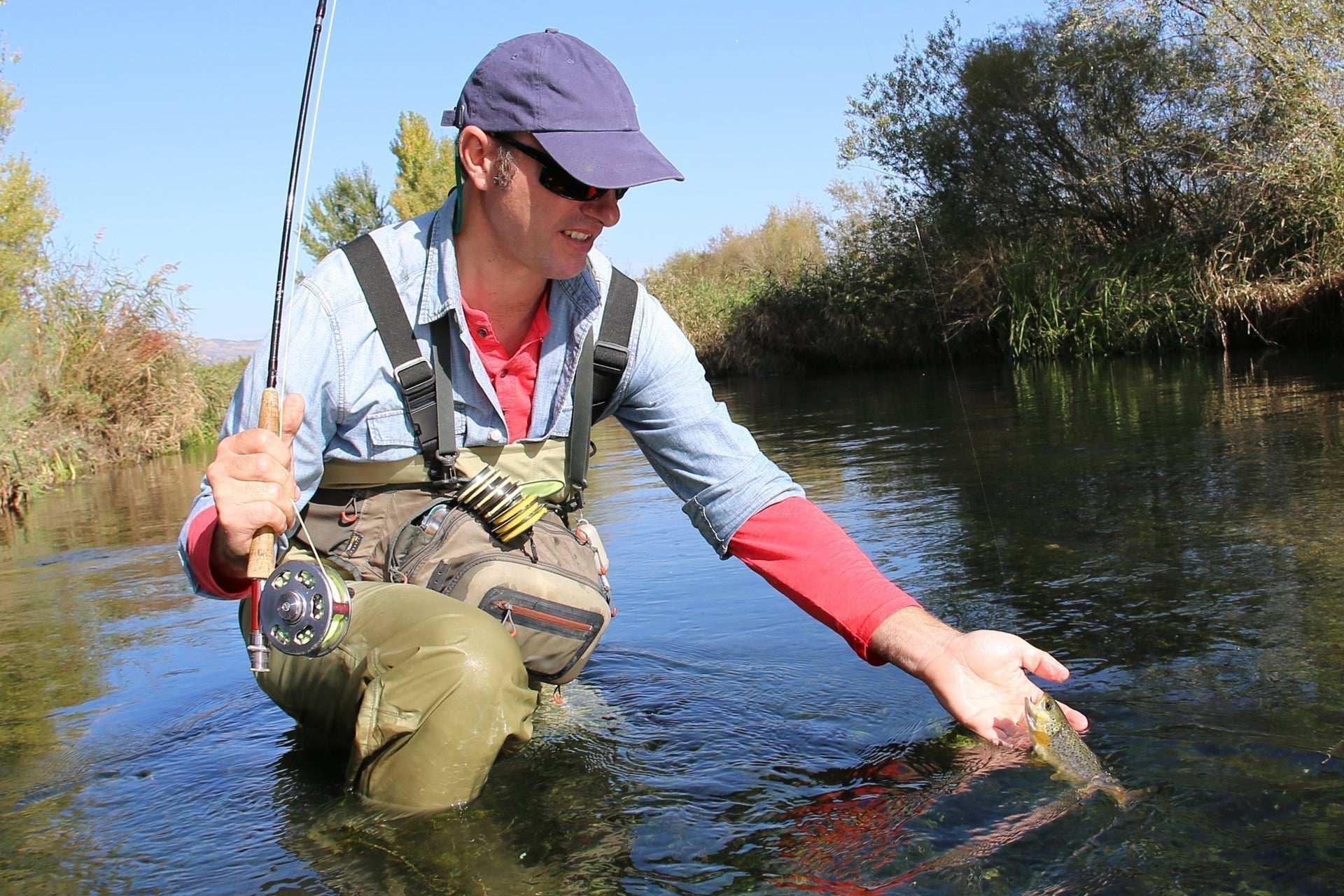 Angler fishing near water with a rod and line, wearing a cap