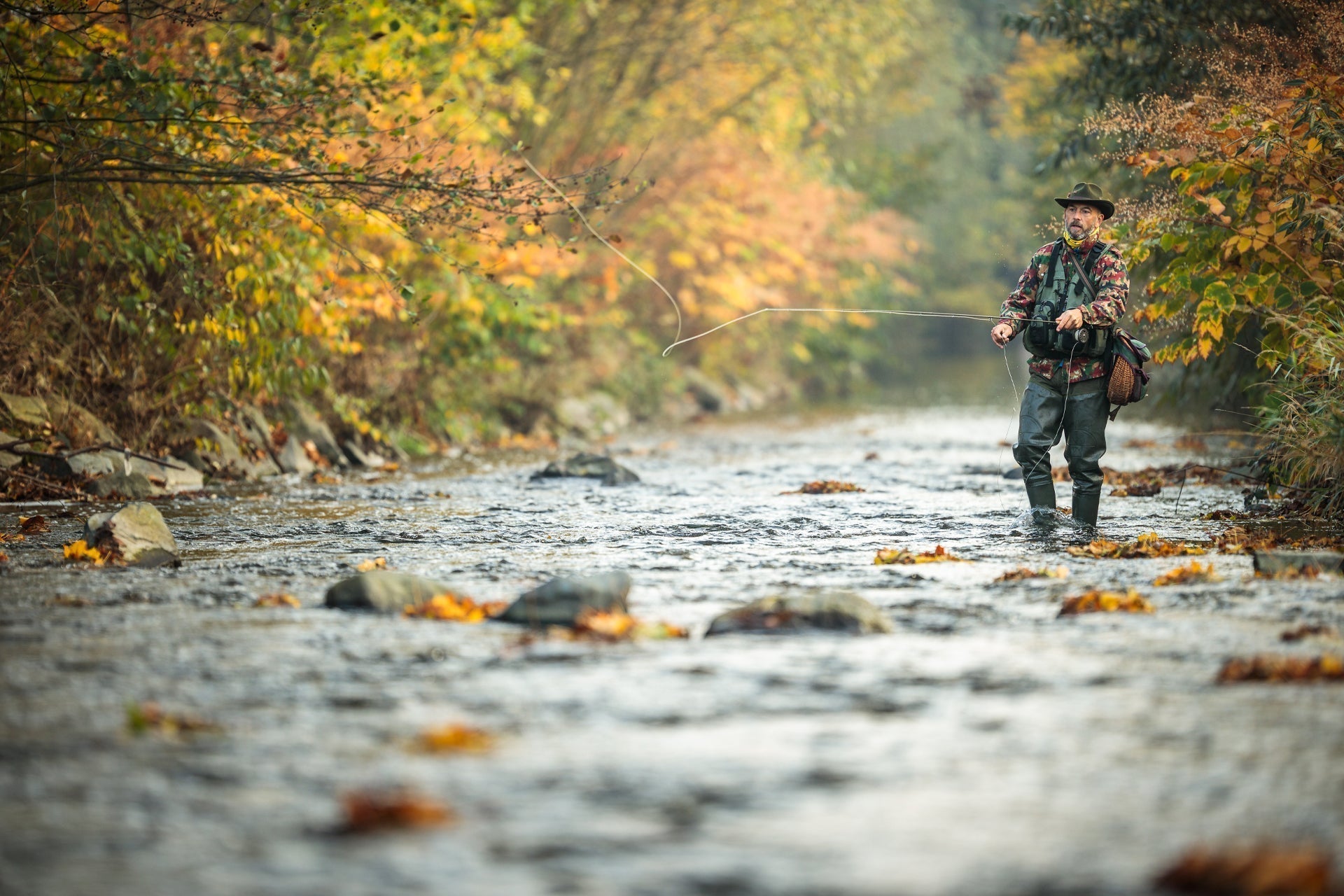 Fly fisherman standing in river holding a fishing rod, fly-fishing setup