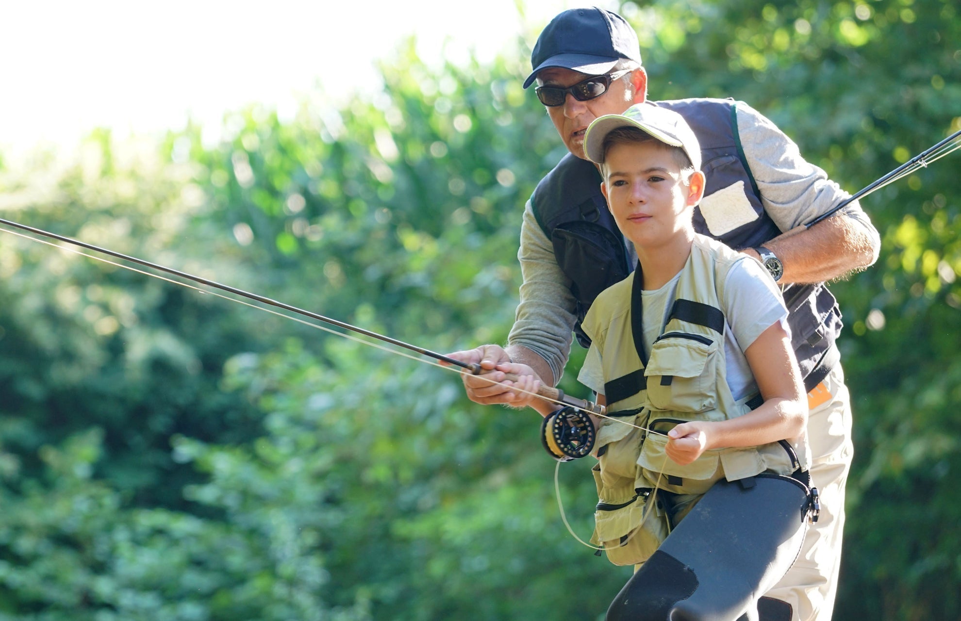 Two anglers fishing together, one holding a fly rod and line