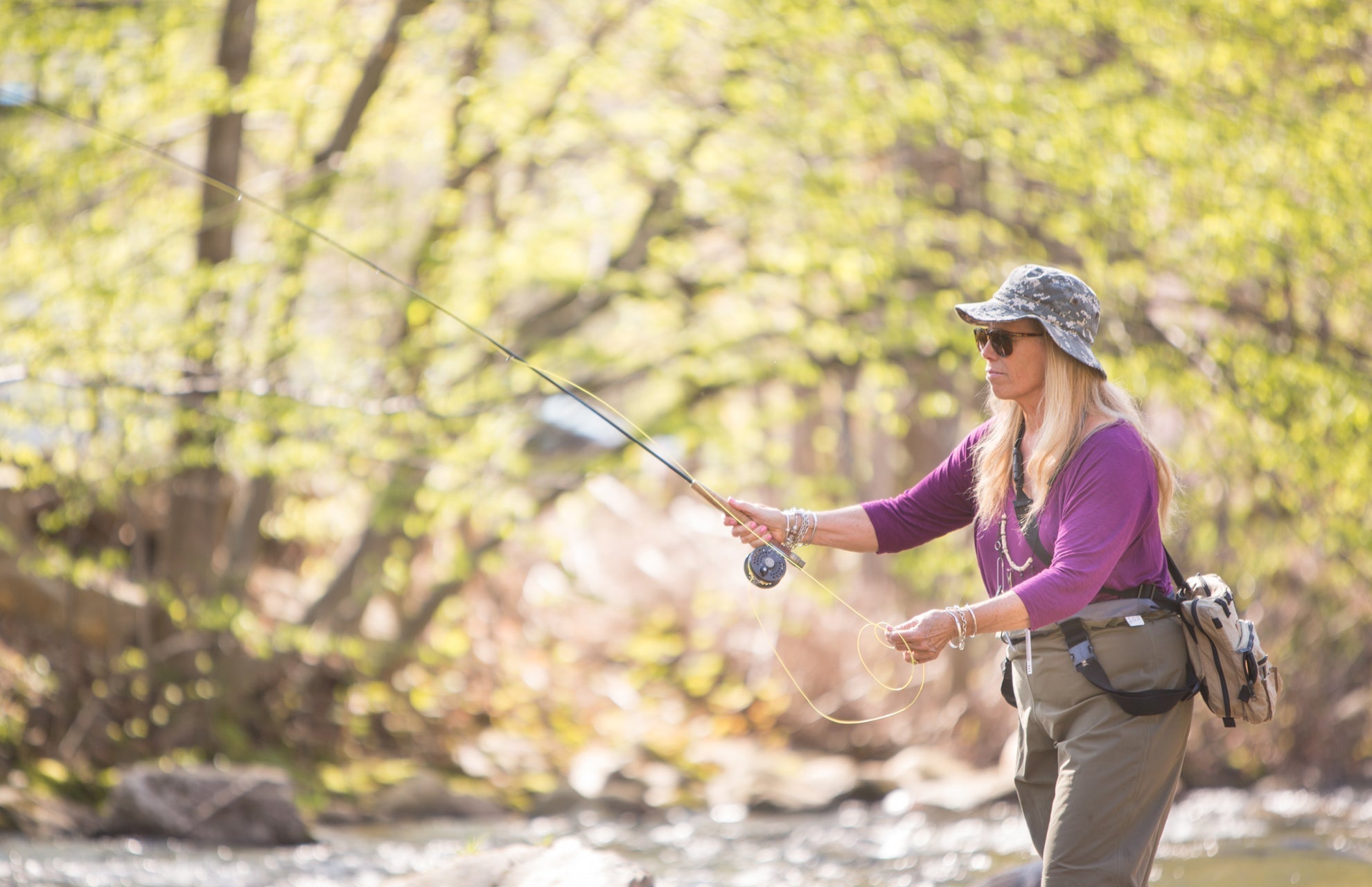 Angler casting with fly rod on river in woods