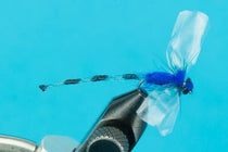 Blue and black feather fishing fly lure with translucent wing and fuzzy blue head