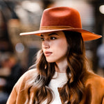 Rust orange wool felt fedora worn with wide flat brim