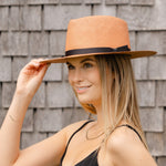 Pink woven Panama hat with dark brown band, worn by model, side view.