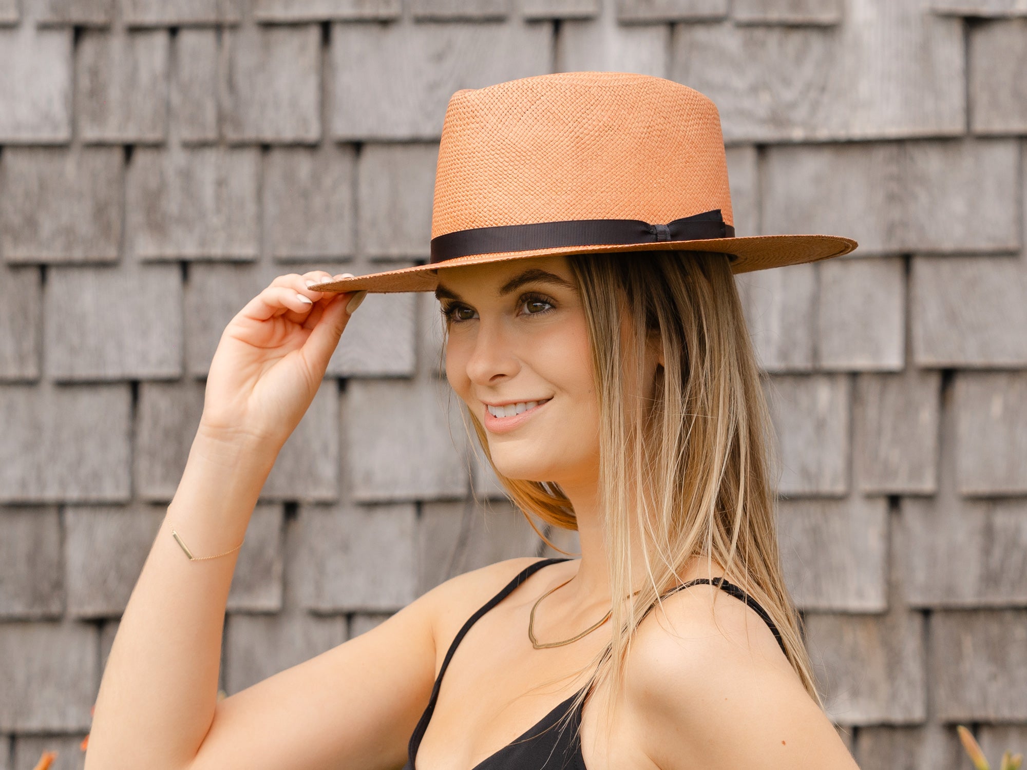 Pink woven Panama hat with dark brown band, worn by model, side view.