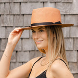 Pink woven Panama hat with dark brown band, worn by model, side view.