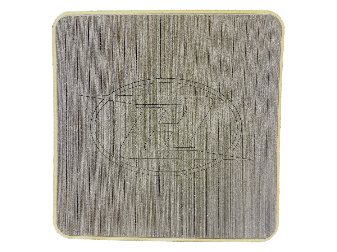 Square deck grip patch with vertical ridges and oval logo, gray with sandy edge.