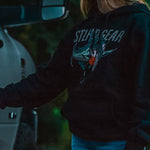 Dark hoodie worn by model with chest fish graphic and orange emblem