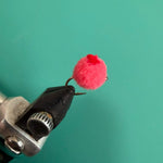 Glo Bug red dot toy with fuzzy pink pom-pom on black metal clip