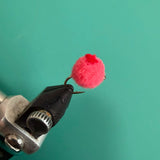 Glo Bug red dot toy with fuzzy pink pom-pom on black metal clip