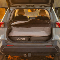 Fitted sleeping bag comforter laid flat in open trunk, beige top and dark brown sides.
