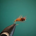 Dark fishing lure with hook and fluffy orange-red tail fibers