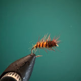 Dark fishing lure with hook and fluffy orange-red tail fibers