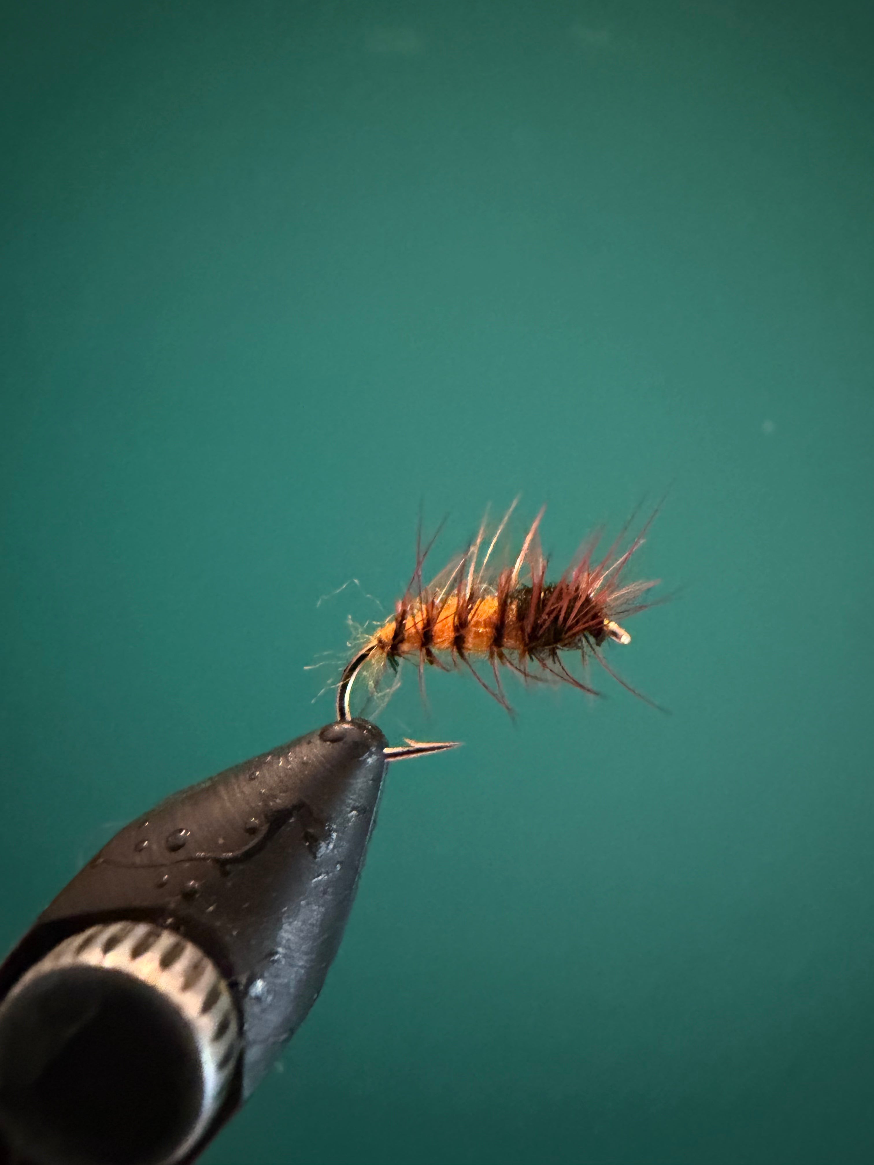 Dark fishing lure with hook and fluffy orange-red tail fibers