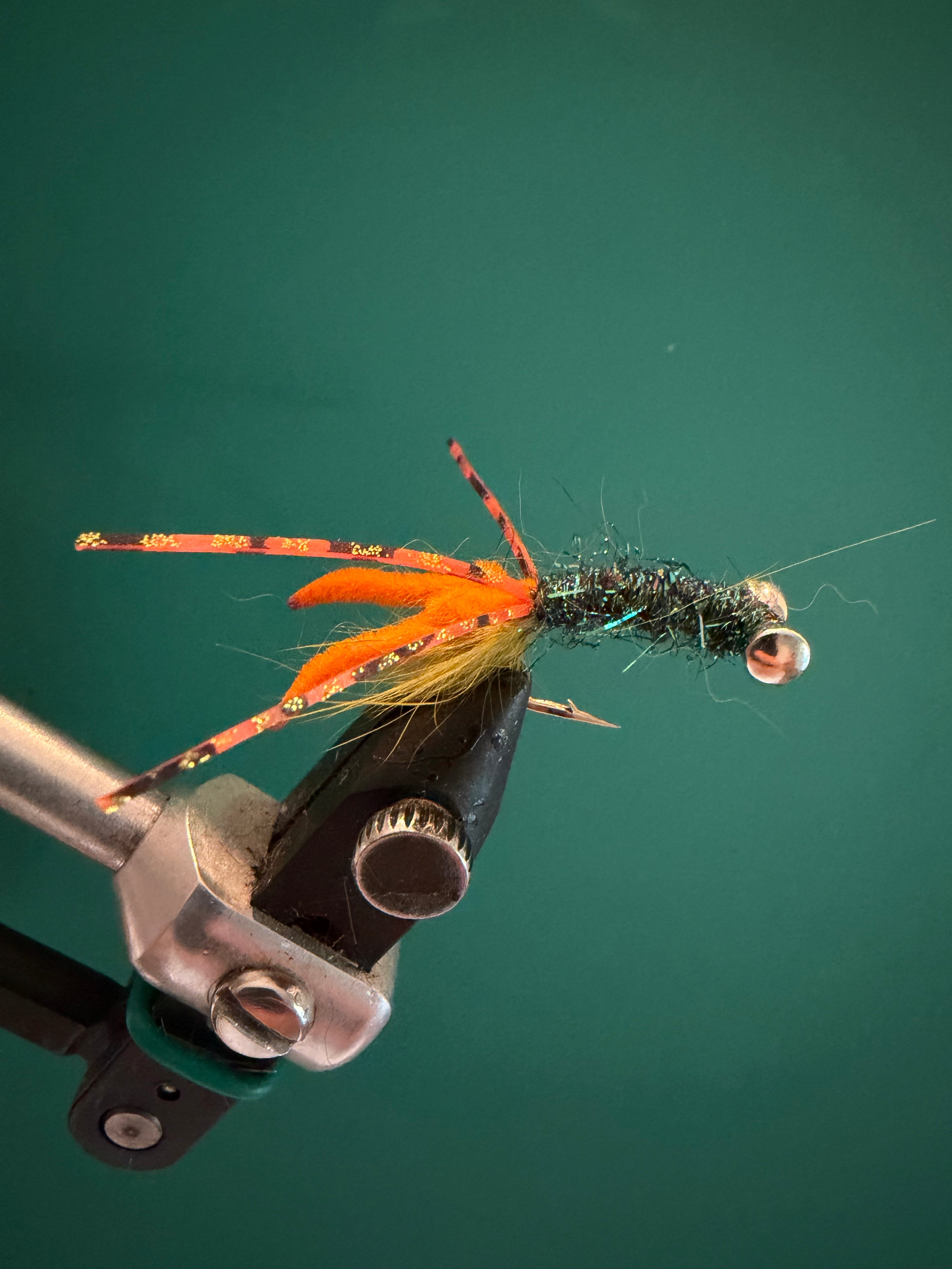 Crawfish-style fishing fly with orange body, fuzzy legs, and black wire head