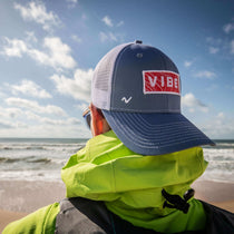 Youth trucker cap in dark navy with white mesh sides and VIBE logo patch