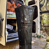Black hanging shower bag attached to an open van door for outdoor rinsing