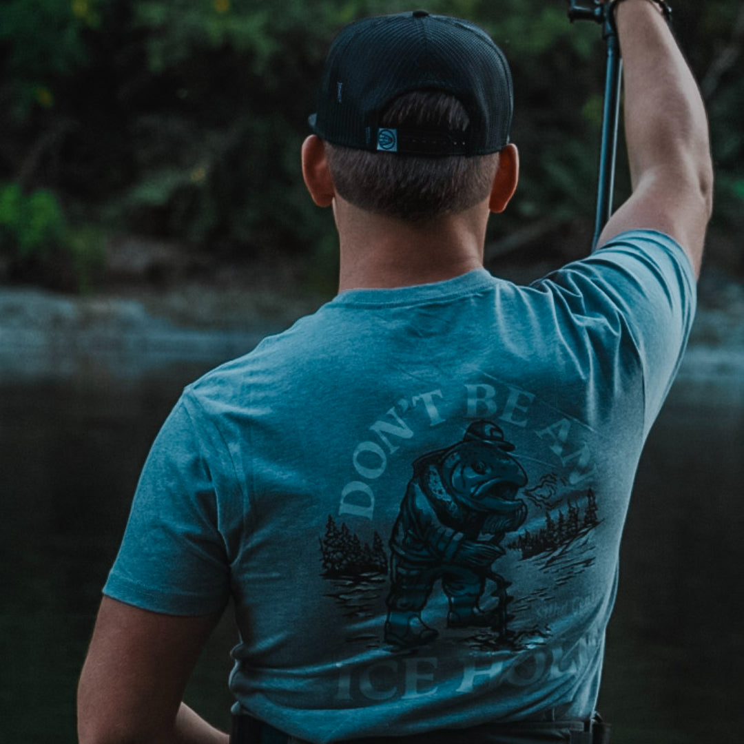Blue T-shirt worn by model, showing back dinosaur “ICE HOLE” print