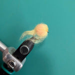 Wool-felt egg figurine in light yellow on a crafting tool clamp