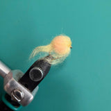 Wool-felt egg figurine in light yellow on a crafting tool clamp