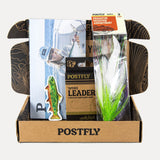 Postfly assortment box with multiple colorful fishing flies and a tapered leader packet
