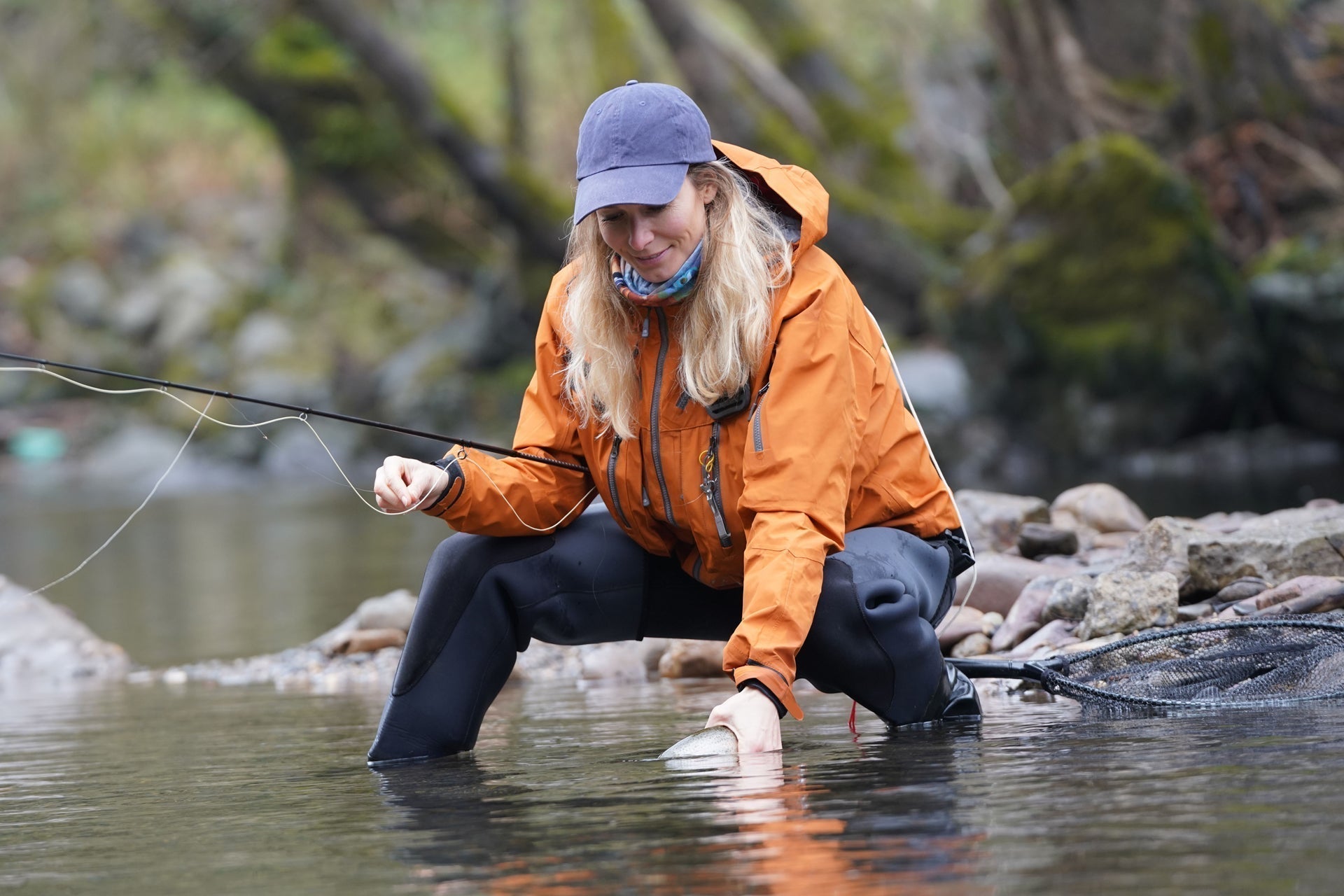 Bead-head nymph fly on line while angler wades in stream