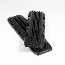 Pair of black traction boards with deep tread channels and grip studs