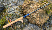 Tenkara fishing rod with cork handle and blue blank lying on rocks