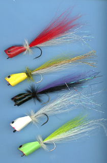 Saltwater popper fishing lures with feather tails; red, yellow, dark, and green bodies