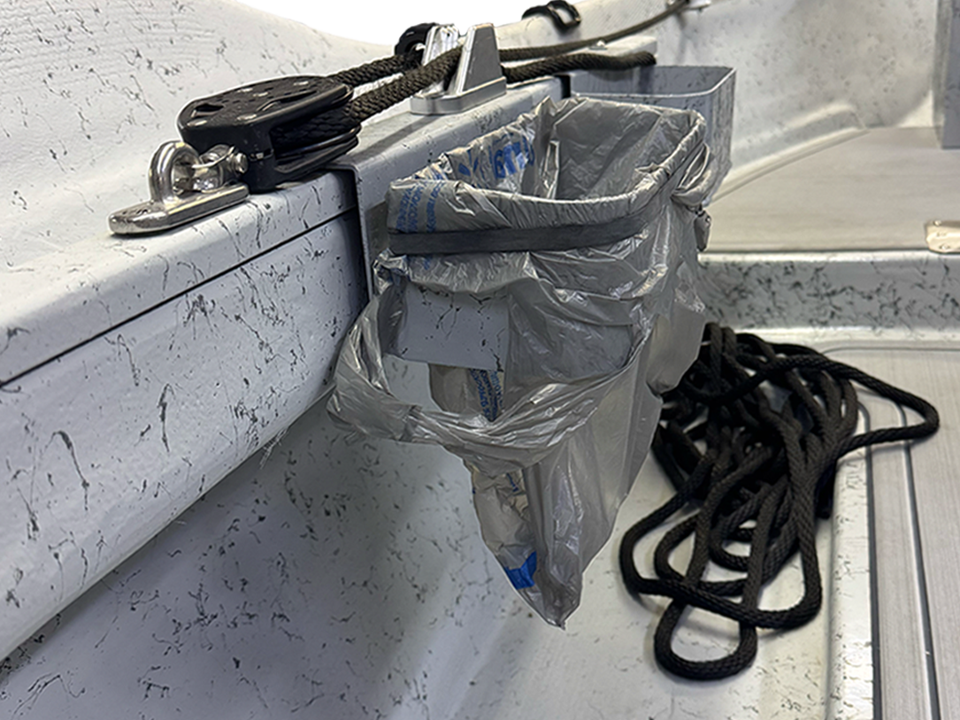 Grey side-mount trash can with attached trash bag and visible mounting hardware
