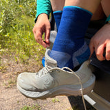 Blue mini crew running socks on foot with trail shoe visible in outdoor setting.