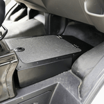 Under-seat storage box with textured top and black base, mounted under seat
