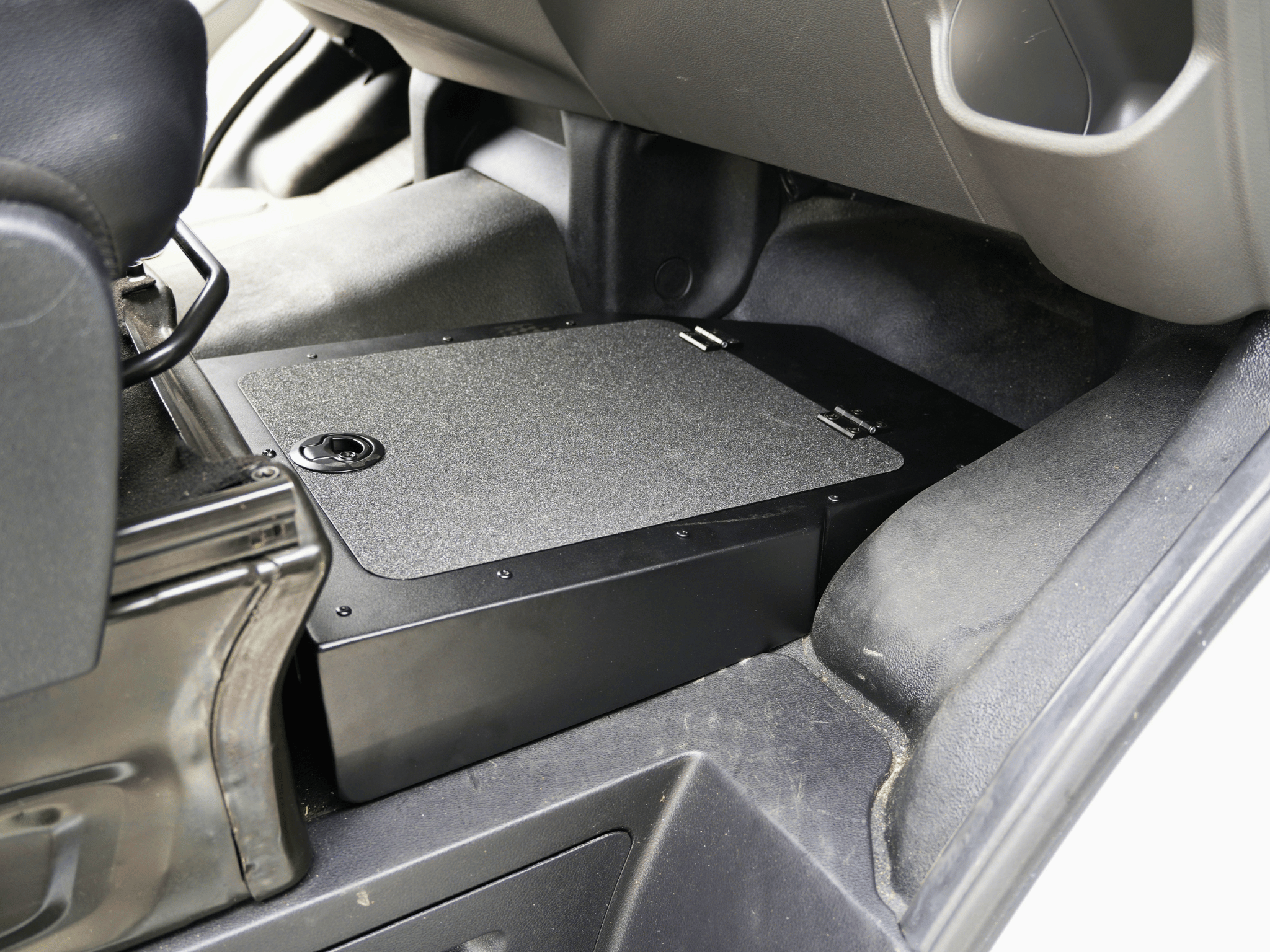 Under-seat storage box with textured top and black base, mounted under seat