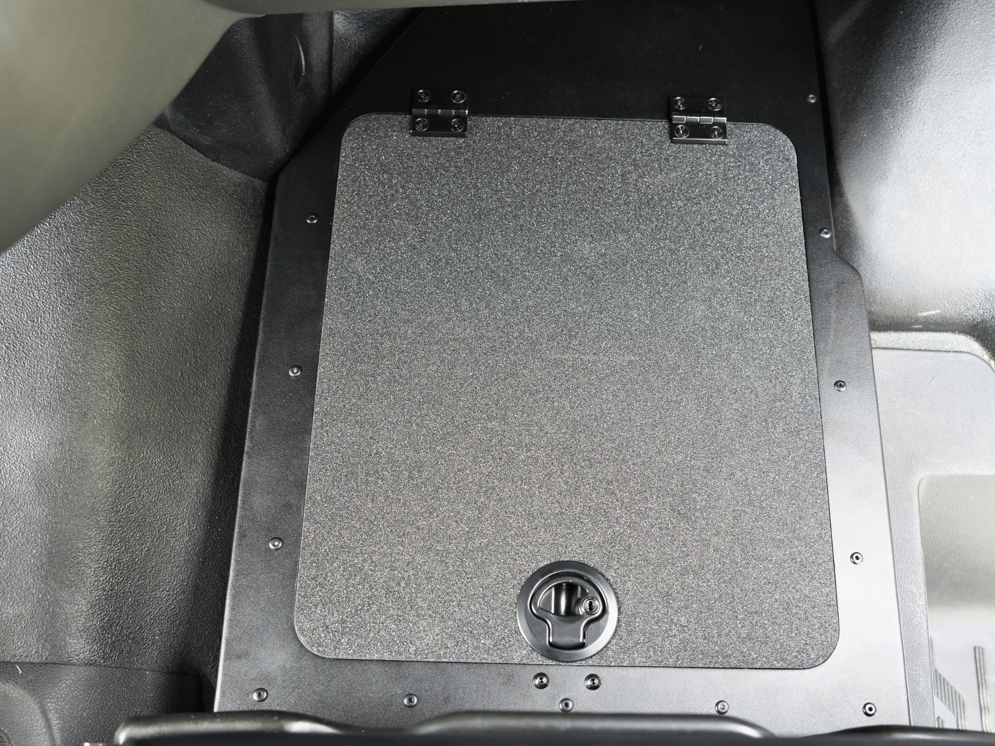 Square under-seat storage lid with textured panel and latch, black base