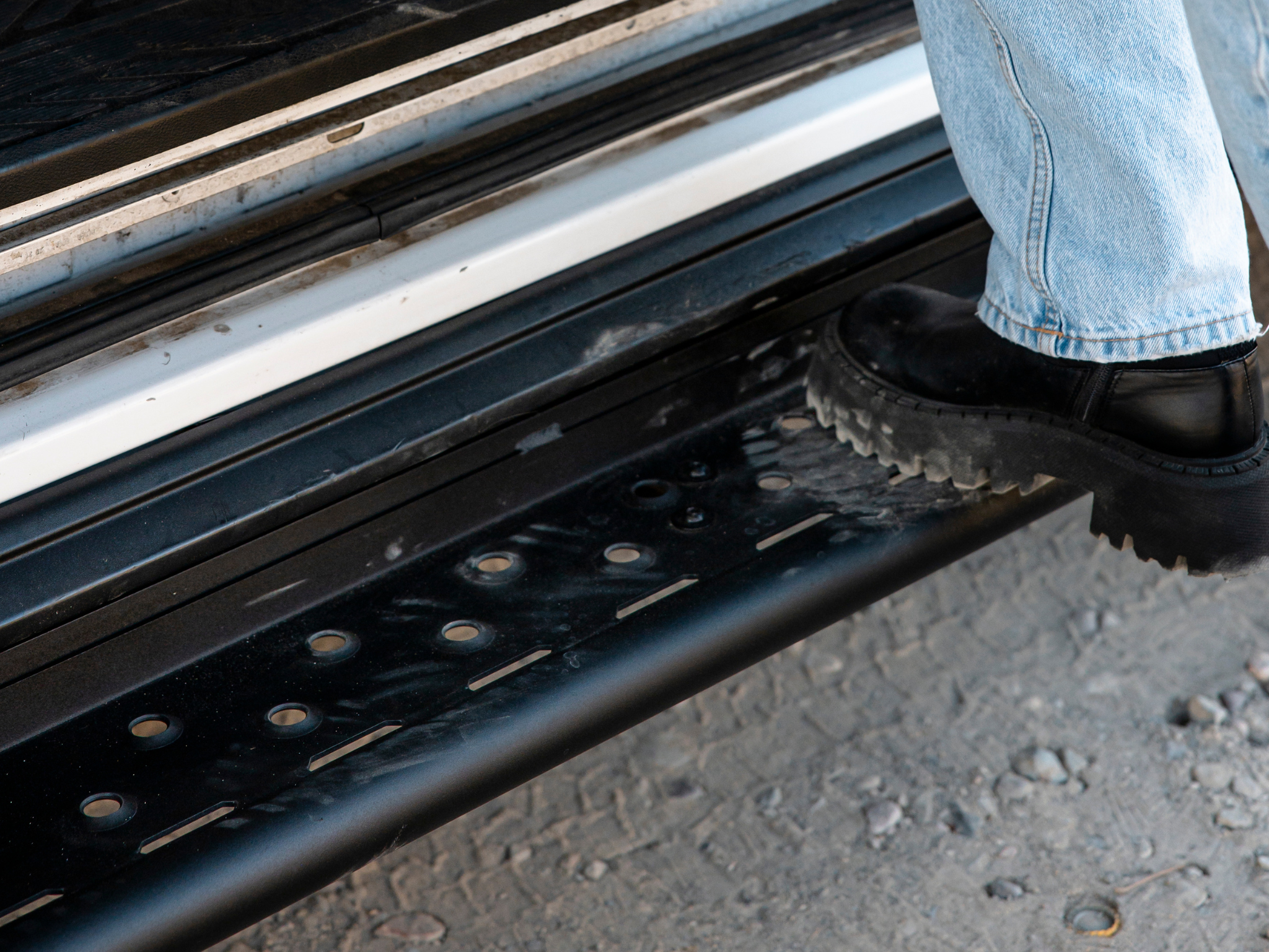 Close-up of black perforated step surface with mounting points