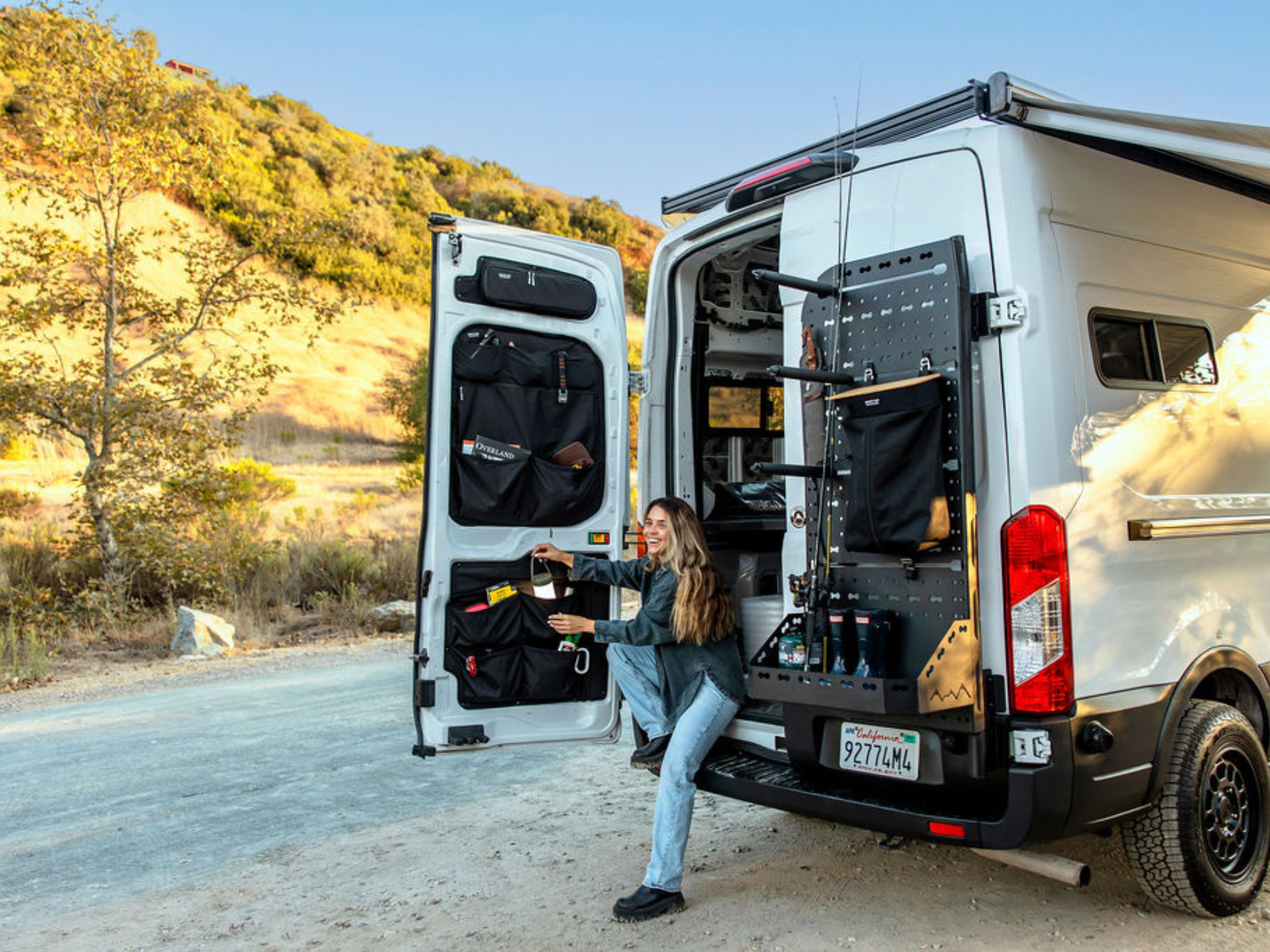 Passenger-side Atlas storage rack with pegboard panel and black organizer bags on open rear doors