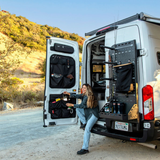 Passenger-side Atlas storage rack with pegboard panel and black organizer bags on open rear doors