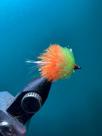 Feather fly fishing lure with orange and green fuzzy tuft