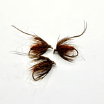 Brown fuzzy pupa fly with spiky hackle wings on a hook, two flies