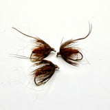 Brown fuzzy pupa fly with spiky hackle wings on a hook, two flies