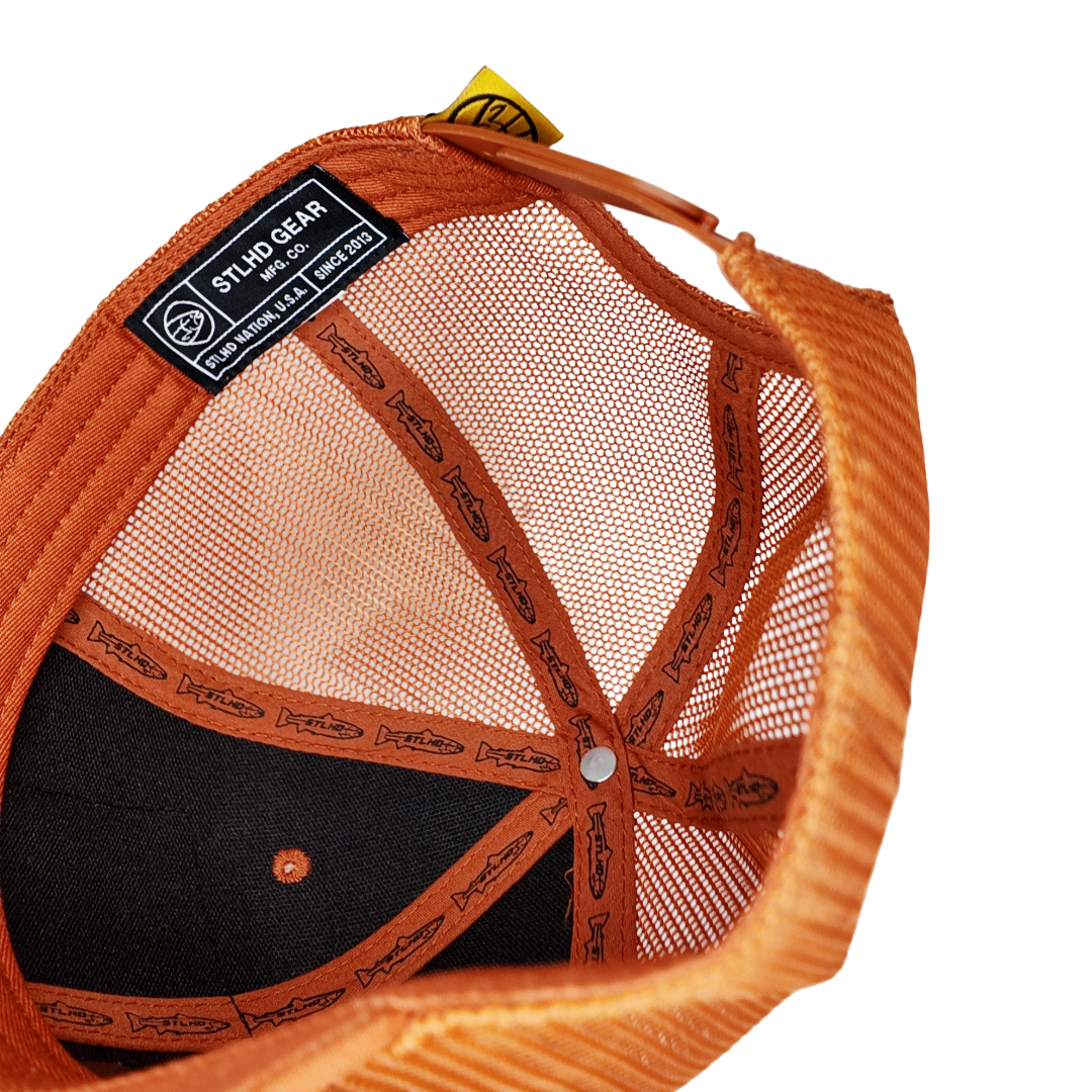 Orange and black cap interior with mesh lining, button closure, and gear label