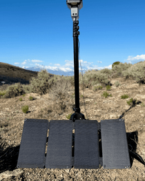 Folding 4-panel solar charger with cable and base stand resting on rocky ground