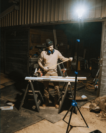 Tripod-mounted work light with lamp head aimed over a work area