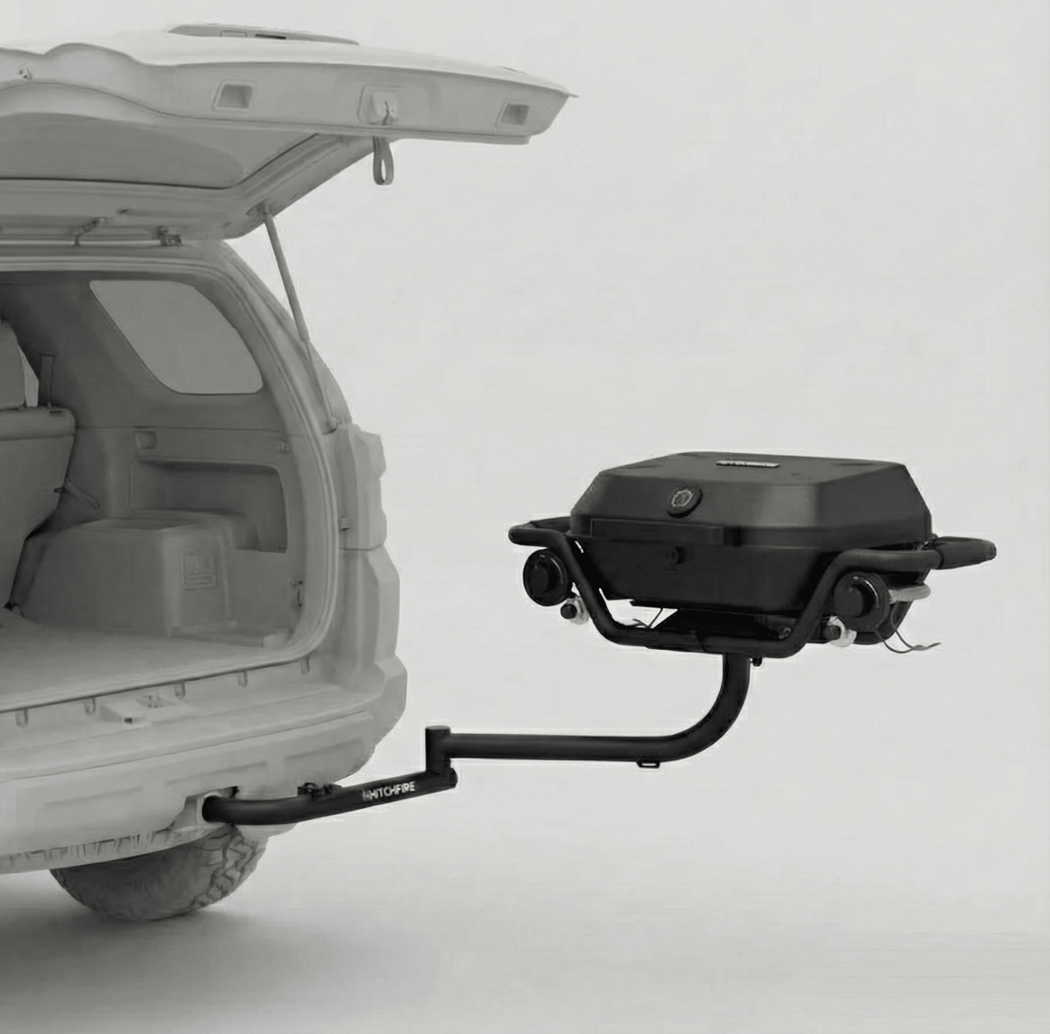 Hitch-mounted propane grill on swing arm with black lid and side shelves