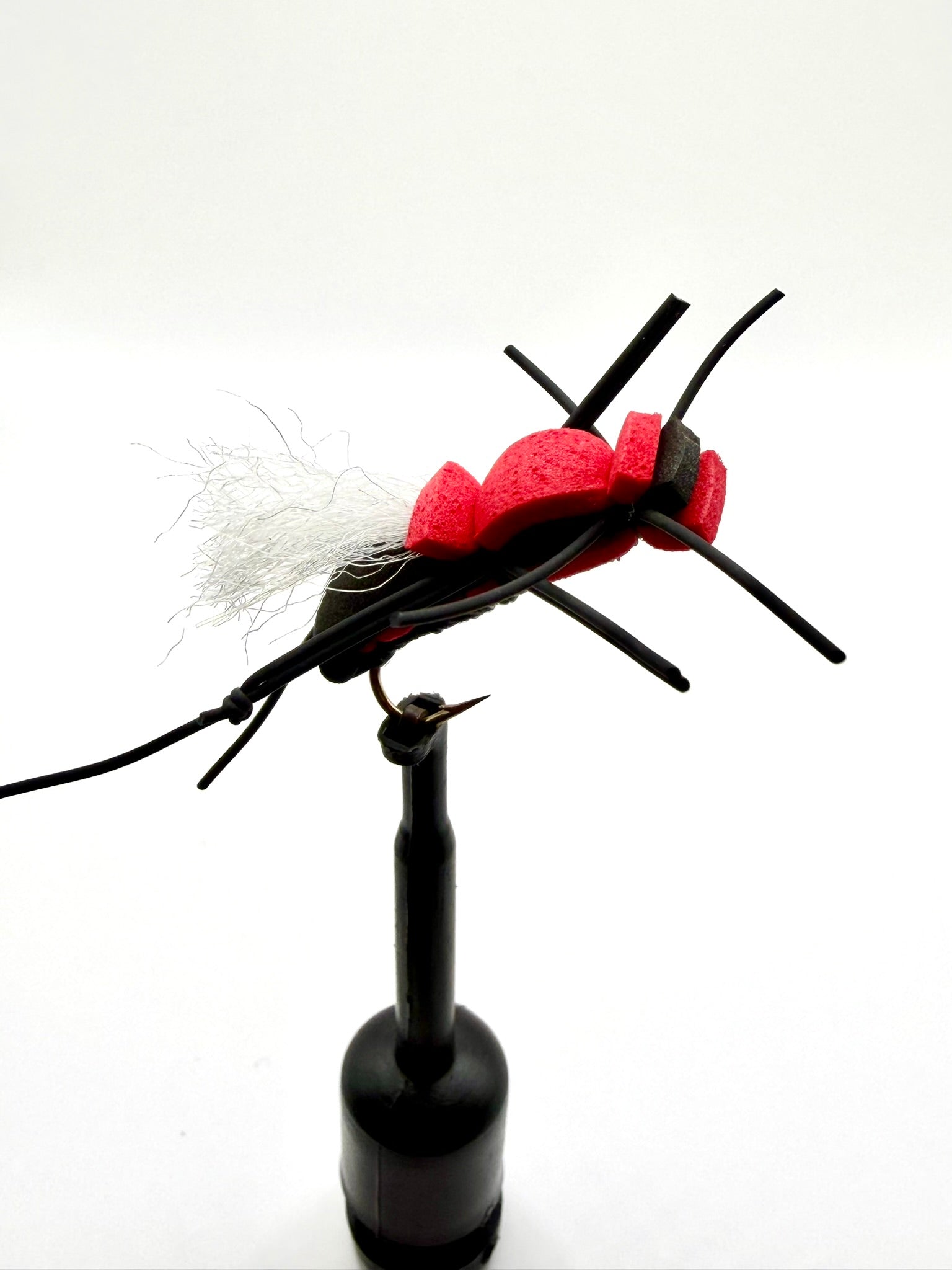 Novelty foam fly fishing lure with red foam head, black legs, and white tuft