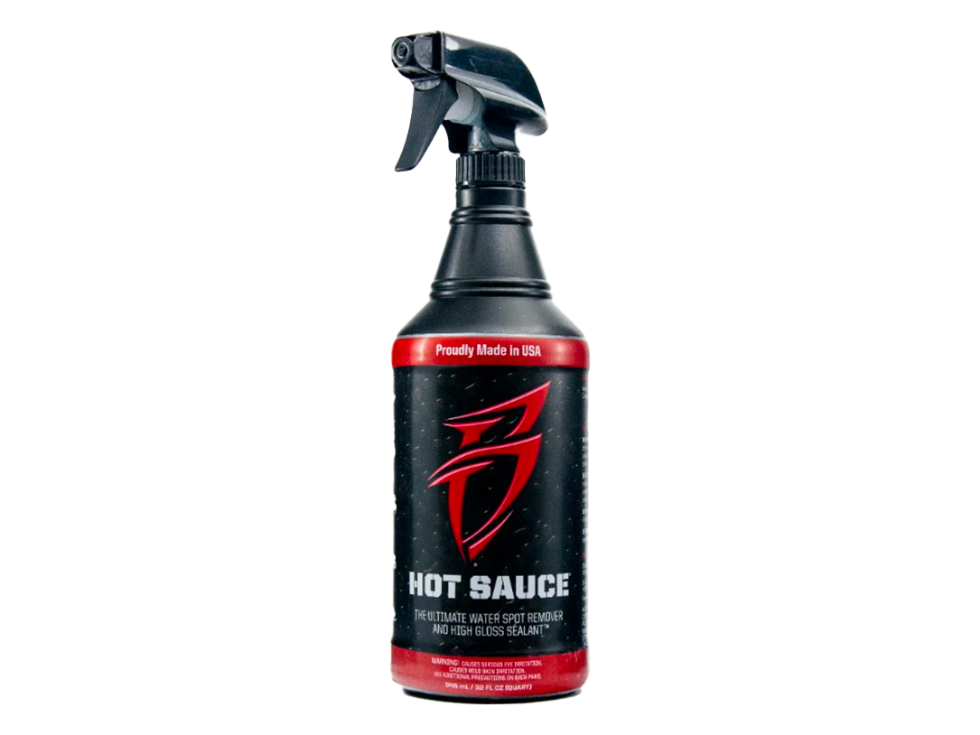 Black spray bottle with trigger sprayer, red label reading HOT SAUCE.