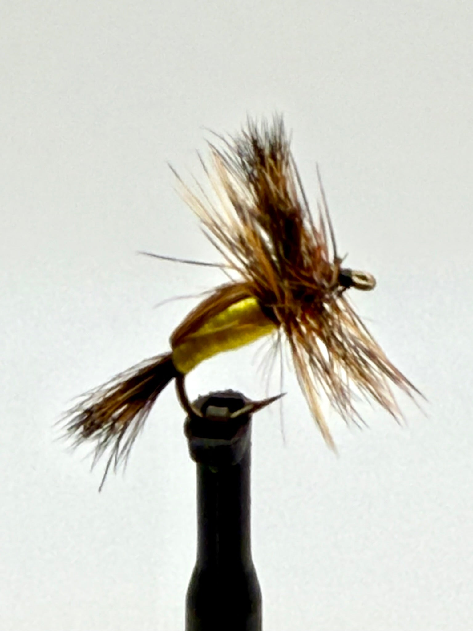Dry fly fishing lure with yellow foam body and brown feather hackle on an eye hook